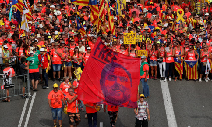 People hold a banner depicting dismissed Catalan Vice President Junqueras as they gather for a rally on Catalonia's national day 'La Diada' in Barcelona