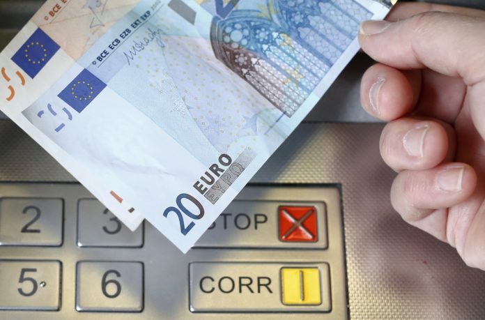 A woman holds a 20 and 50 Euro bank notes in front of an ATM in this illustration picture taken in Bern